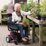 Lady in power chair next to raised planter lifting plant pot