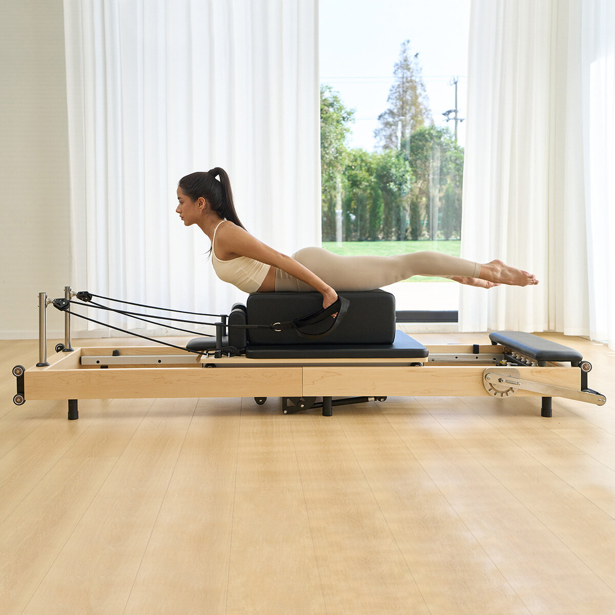 Lifestyle image of a woman using the reformer Lifestyle image of a woman using the reformer