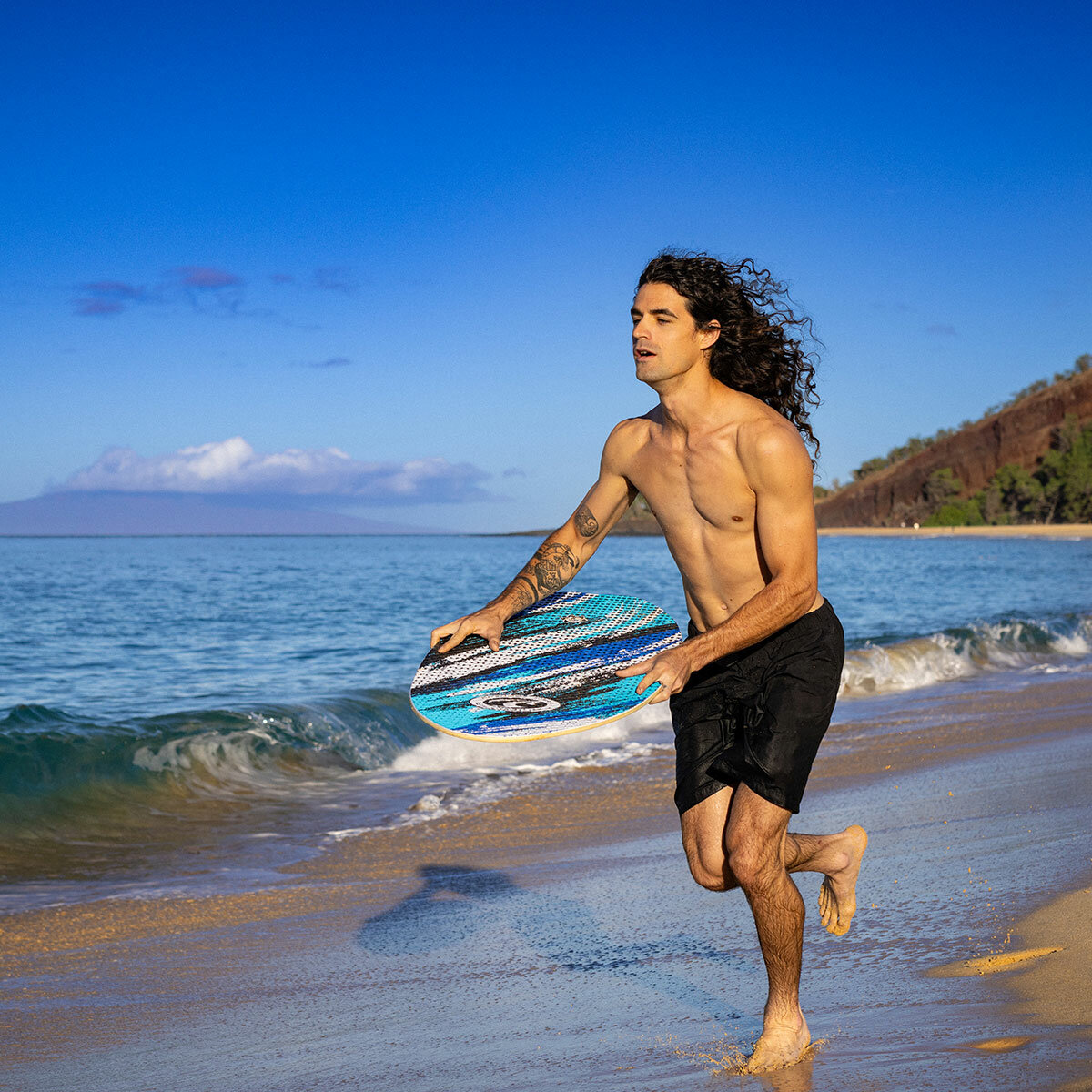Lifestyle image of a man running along the beach with the skimboard Lifestyle image of a man running along the beach with the skimboard