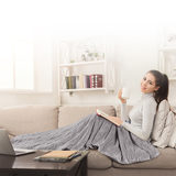 Lifestyle image of woman on sofa covered with weighted blanket