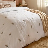 Soft white duvet set with a subtle scattered floral pattern, neatly laid across a made bed