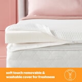 A white mattress topper with elastic corner straps fitted neatly over a mattress.