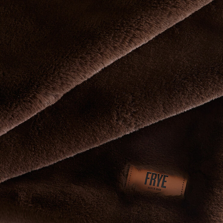Close-up of dark brown faux fur throw showing stitched leather brand tag