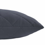 Quilted blue body pillow with diamond stitching placed in front of two white pillows on a neatly