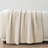 Taupe plaid throw staged on white sofa in a lifestyle image
