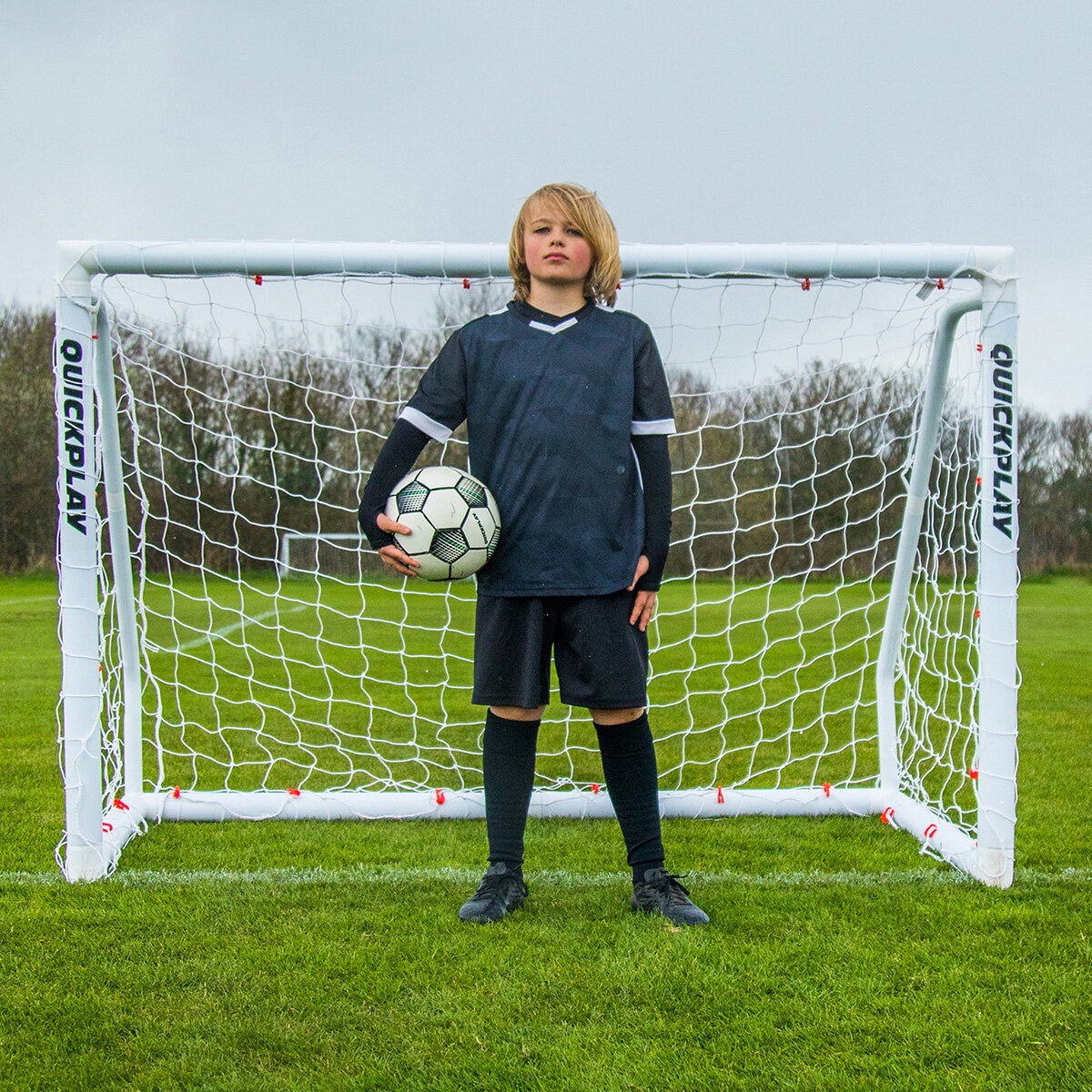 Lifestyle image of a goalkeeper stood in from of the goal, holding a ball Lifestyle image of a goalkeeper stood in from of the goal, holding a ball