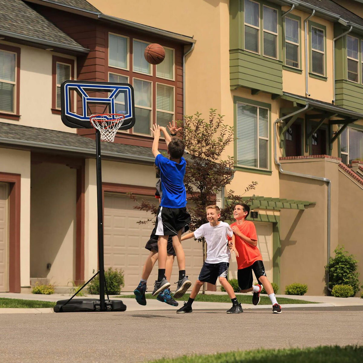 Lifestyle image of four children playing basketball, one of which is shooting the ball into the 44 inch Portable Basketball Hoop