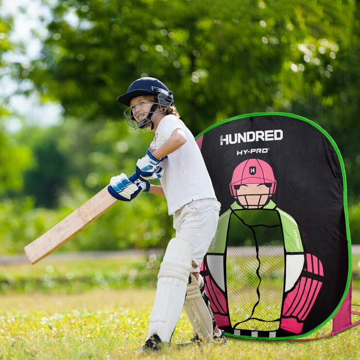Lifestyle image of a child in front of the pop up wicket keeper, bat in hand ready to hit the ball