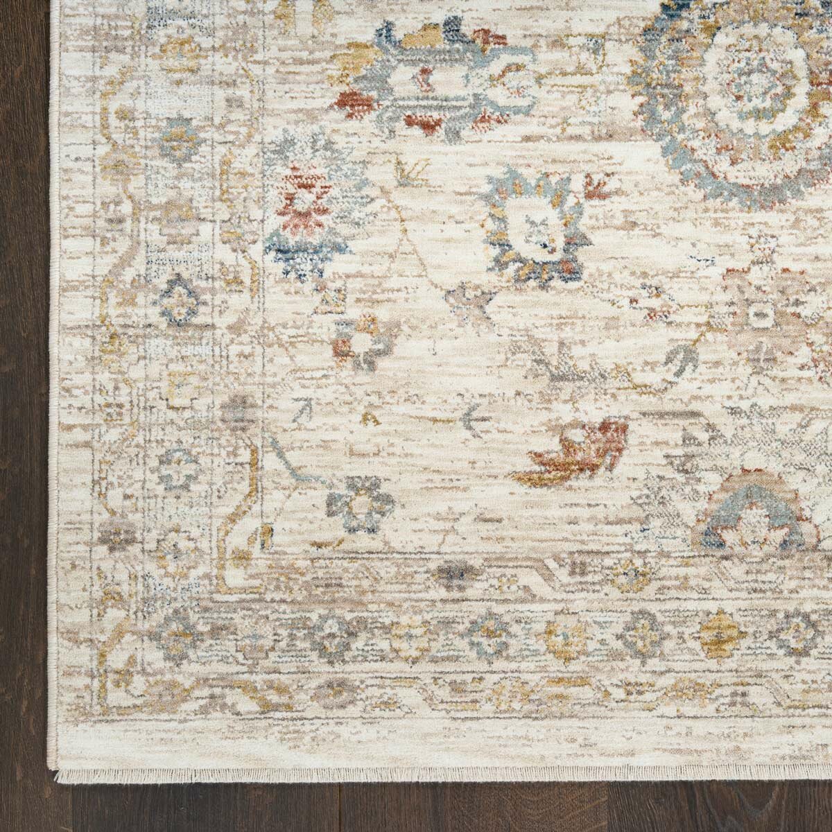 Beige rug with symmetrical floral and geometric pattern in muted blue, red, yellow, and grey
