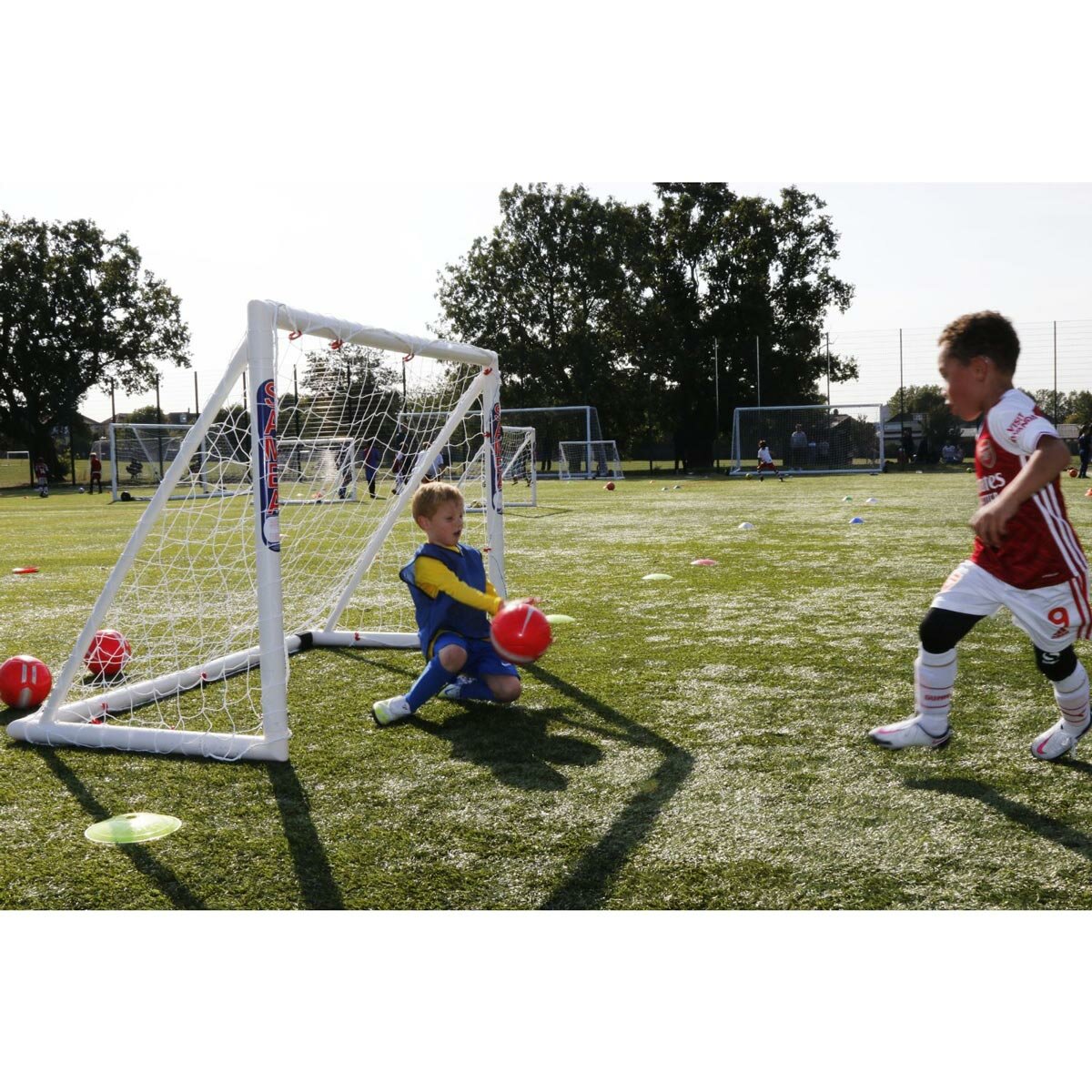 Lifestyle image of two children playing football using the goal Lifestyle image of two children playing football using the goal