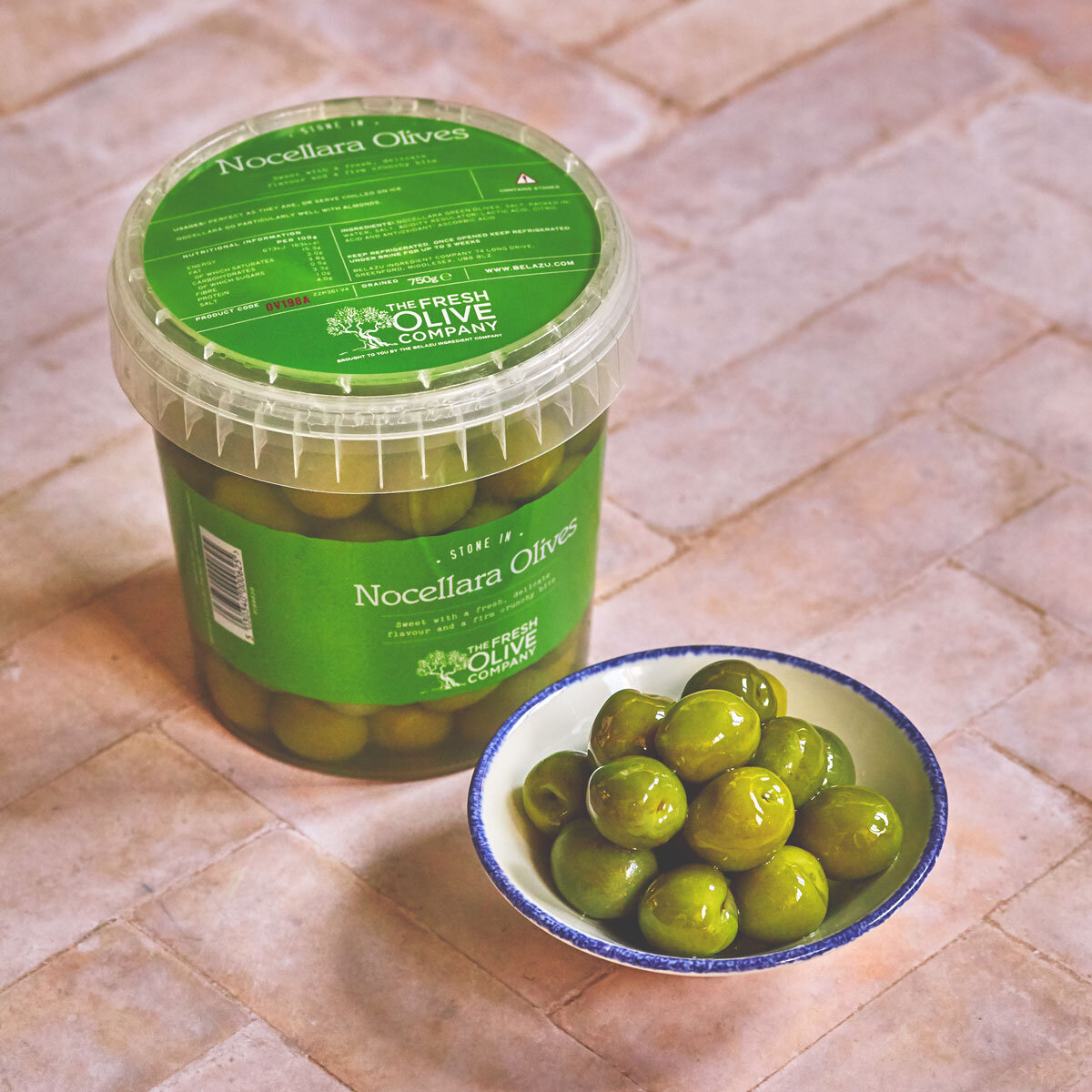 Pot of The Olive Company Nocerllara Olives 750g with bowl of olives