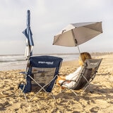 Lifestyle image of two people on the beach, one in the beach chair Lifestyle image of two people on the beach, one in the beach chair