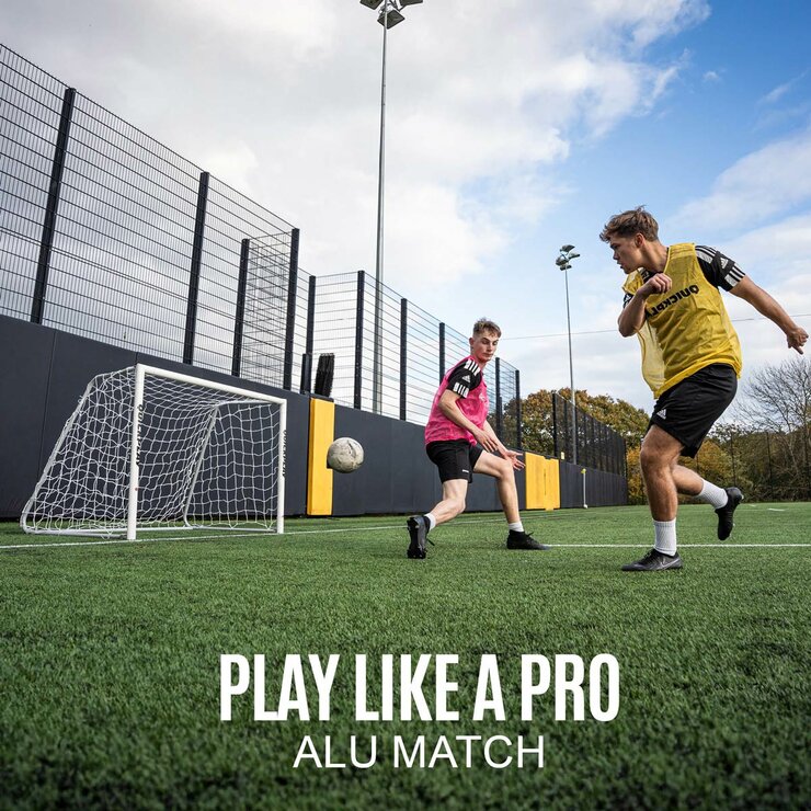 Lifestyle image showing two people playing football using the goal Lifestyle image showing two people playing football using the goal