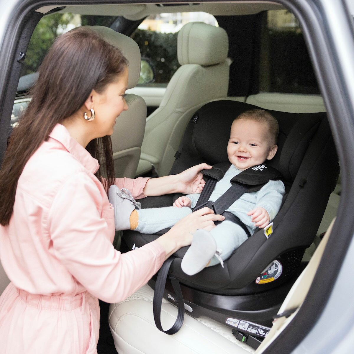 Lifestyle image of a mother putting child into the car