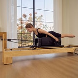 Lifestyle image of a woman using the reformer Lifestyle image of a woman using the reformer