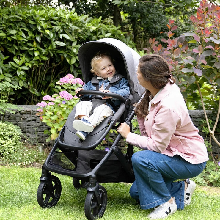 Lifestyle image of a woman crouched next to the stroller, looking at her baby