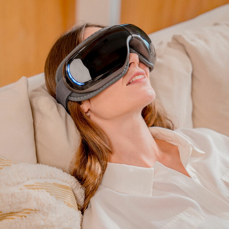 Lifestyle image of model using Renpho Artimis Blush Light Mask whilst sitting on sofa