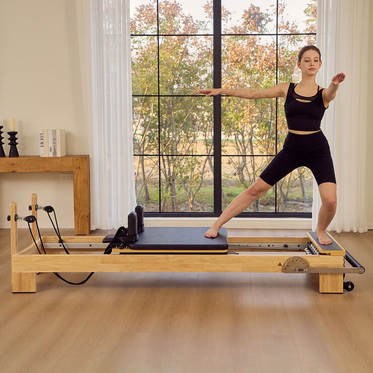 Lifestyle image of a woman using the reformer Lifestyle image of a woman using the reformer