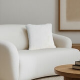 Super soft faux fur pillow in ivory staged on sofa