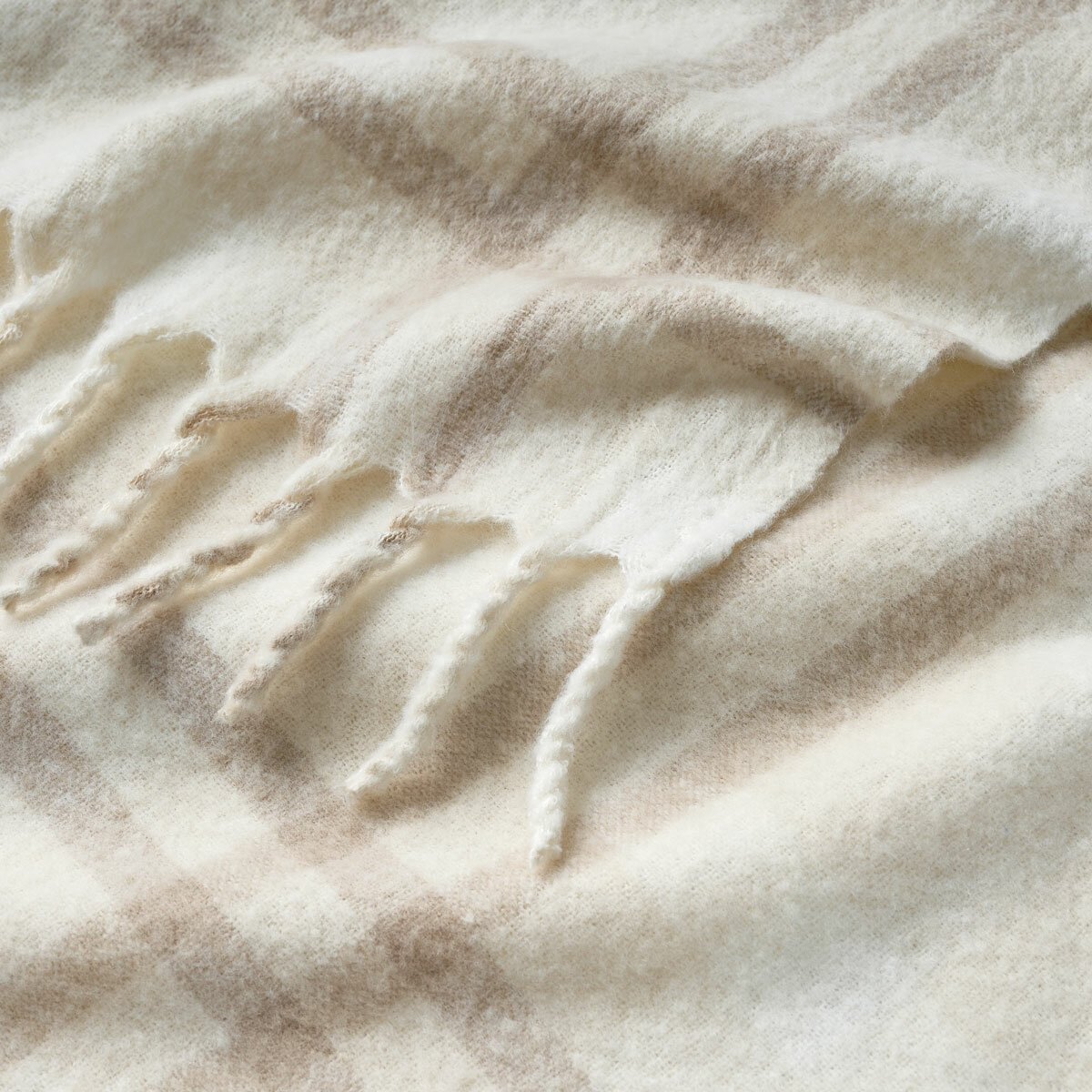 Close up of Beige Faux Mohair Throw, showcasing fringed border and soft texture