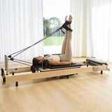 Lifestyle image of a woman using the reformer Lifestyle image of a woman using the reformer