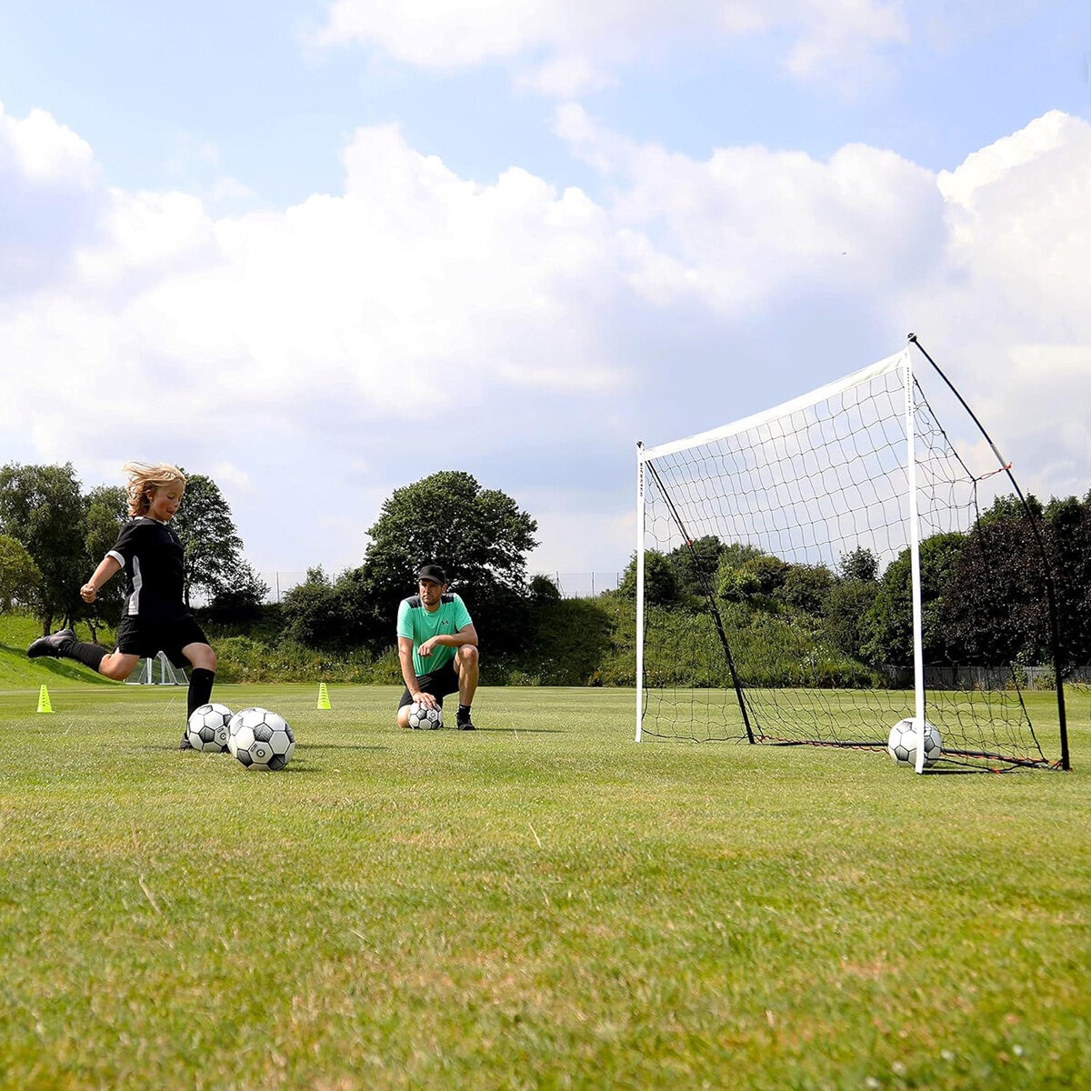 Lifestyle image of a child kicking balls into the goal