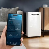 Lifestyle image of f Pro Breeze 20L Dehumidifier with Max Extraction, Laundry Mode showing Smart App Control on a phone