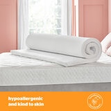 A white mattress topper with elastic corner straps fitted neatly over a mattress.