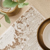 Textured rug with a distressed abstract pattern in beige, cream and light brown, showing irregular brushstroke-style detailing. Textured rug with a distressed abstract pattern in beige, cream and light brown, showing irregular brushstroke-style detailing.