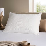 White pillow with a raised geometric zigzag pattern, shown on a bed
