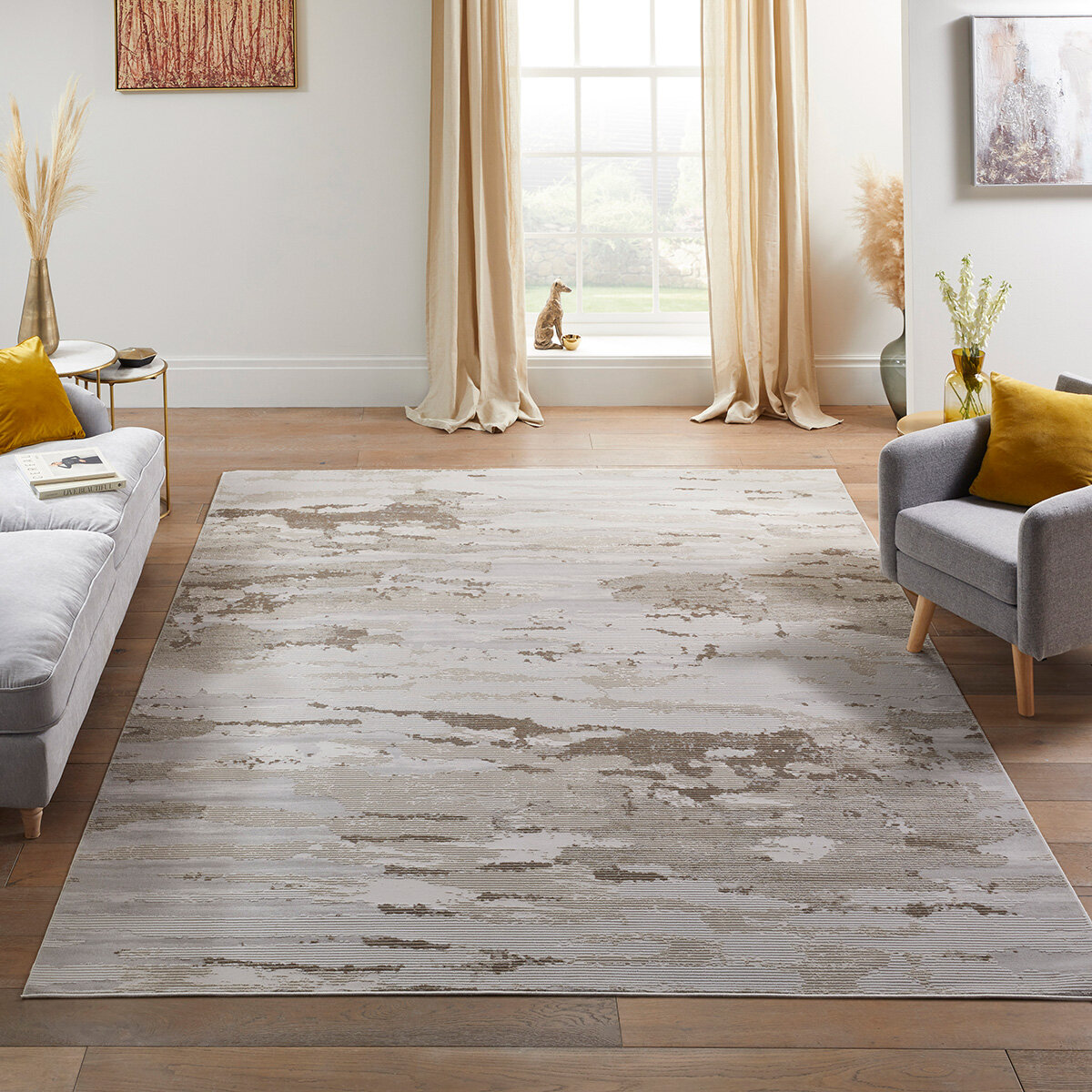 Large abstract rug in beige and grey tones, placed in a modern living room with minimal decor.