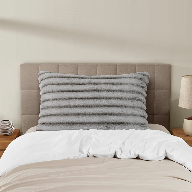 XL ribbed pillow with a plush texture propped against a tufted headboard on a neatly made bed