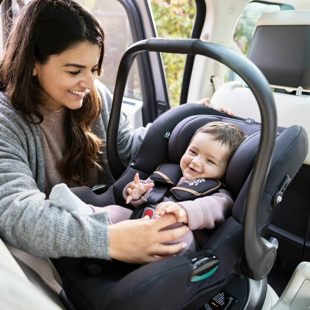 Lifestyle image of woman putting child into car seat