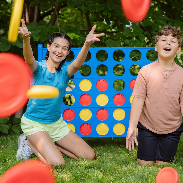 Lifestyle image of two children throwing the game pieces at the camera