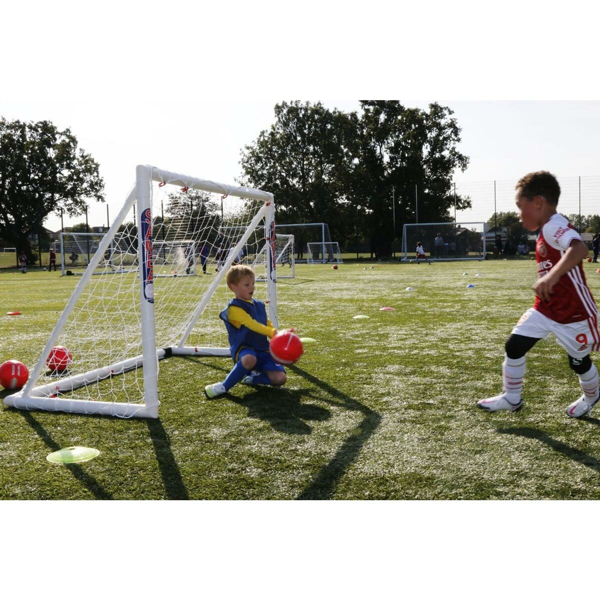 Lifestyle image of two children playing football using the goal