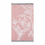 Pink towel with a white bird and branch design, grey borders, and “TED BAKER” branding in the corner