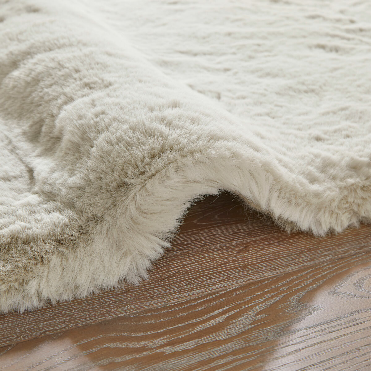Cream faux fur rug with thick, fluffy texture on wooden floor