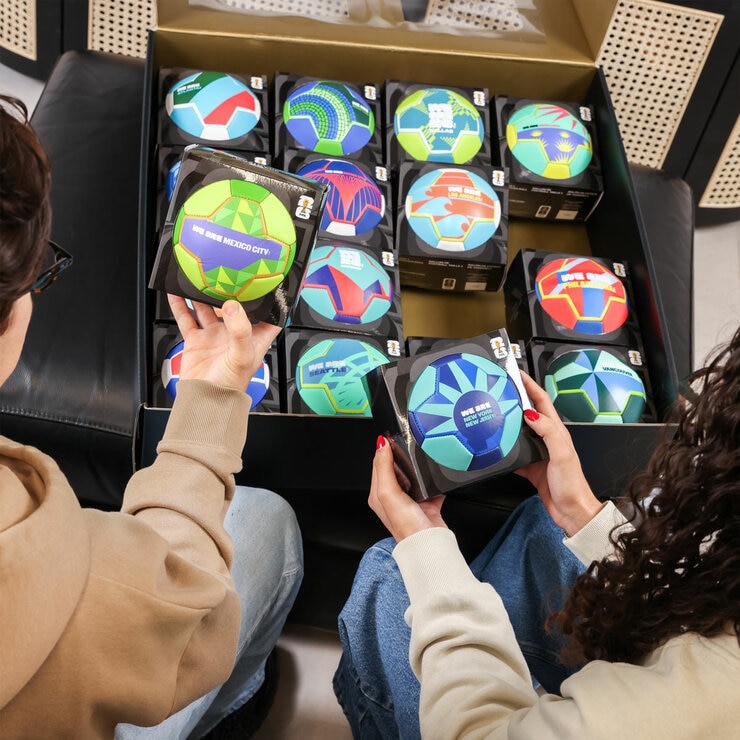 Lifestyle image showing two people looking at the different footballs in the box