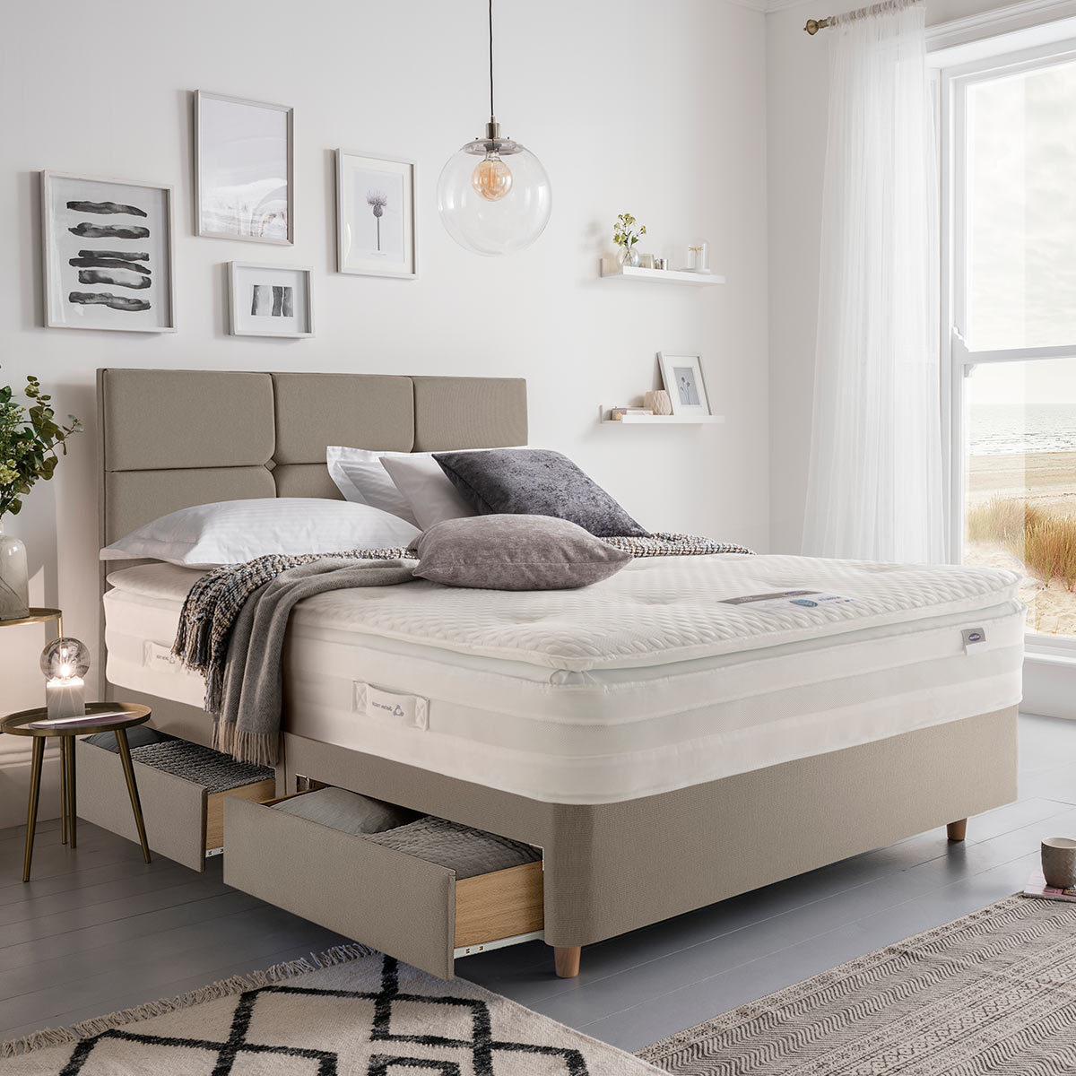 Lifestyle image of made up bed in sandstone in front of window showing beachside