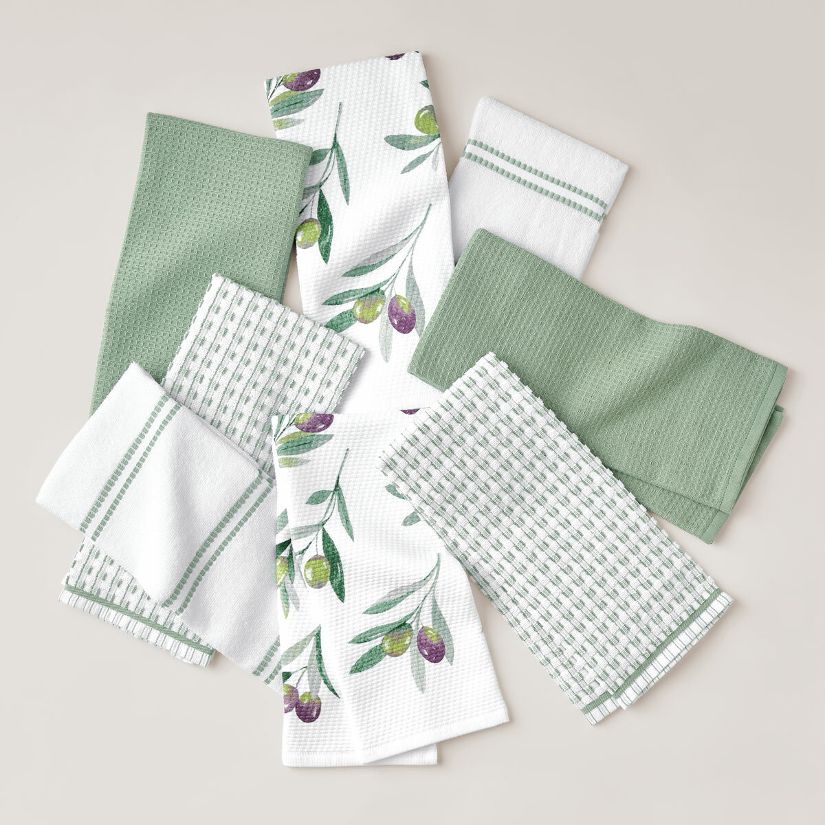 Eight green-themed tea towels arranged in a circle on a light surface, featuring solid, striped, checkered, and olive branch print designs Eight green-themed tea towels arranged in a circle on a light surface, featuring solid, striped, checkered, and olive branch print designs