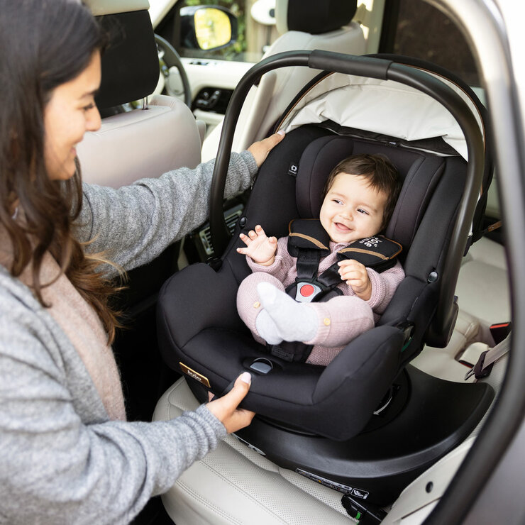 Lifestyle image of woman putting child into car seat