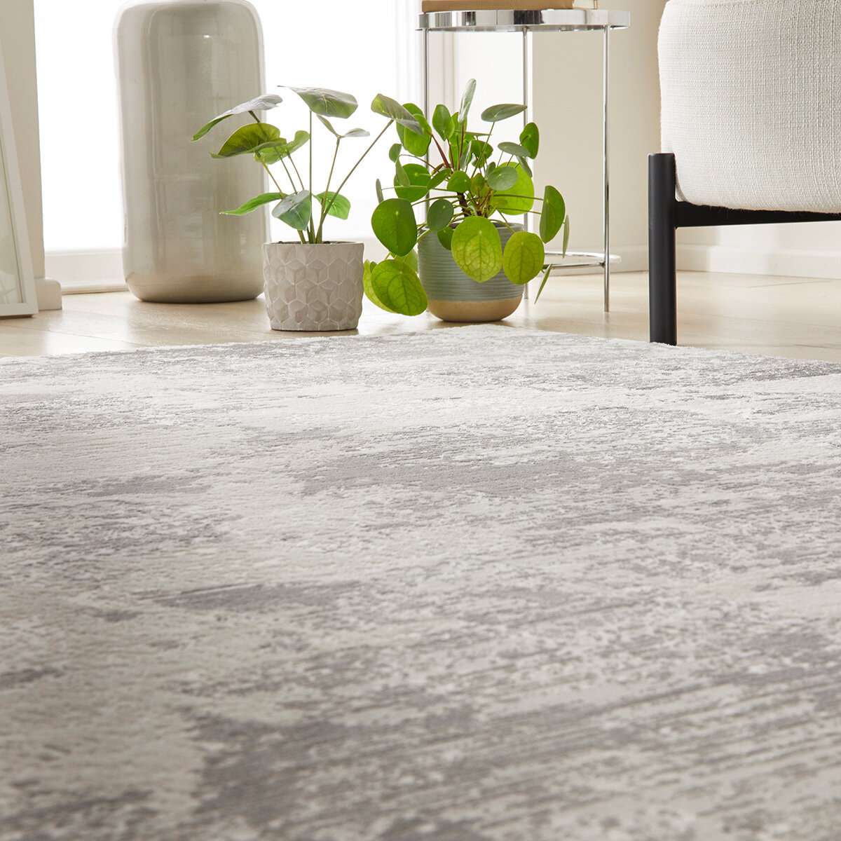 Grey-toned rug with a soft abstract design in grey and cream, styled with a white sofa and gold side table on light wood flooring.