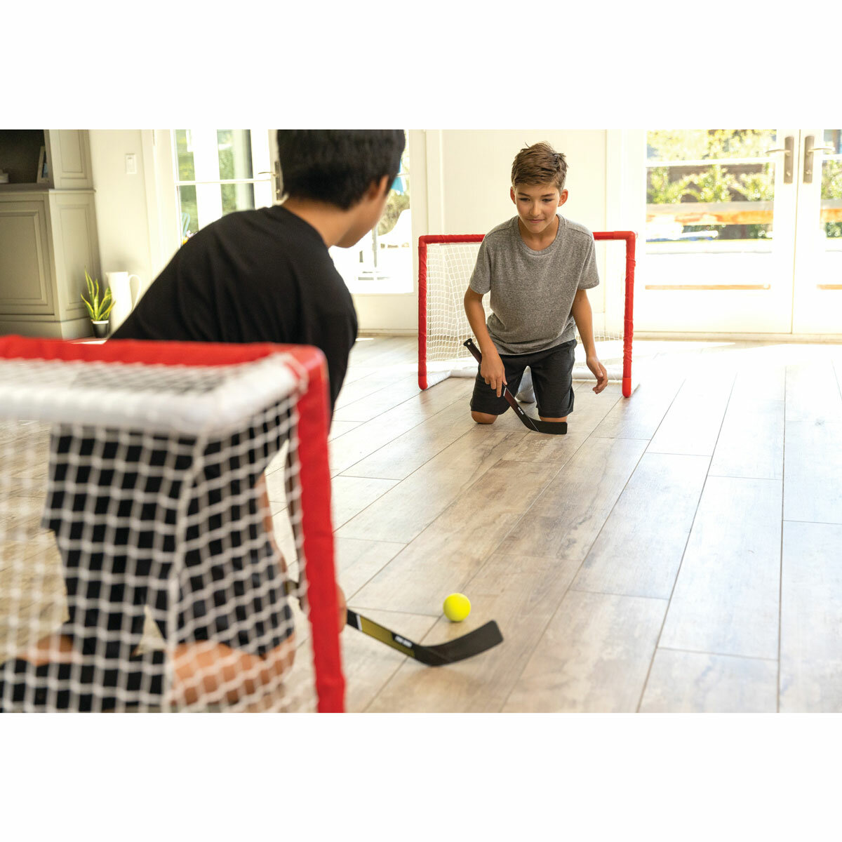 Lifestyle image of two children playing on the floor with the SKLZ Pro Mini Hockey