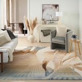 Large rug with an abstract pattern in beige, brown and blue, placed in a modern living room with neutral furniture and soft textures.