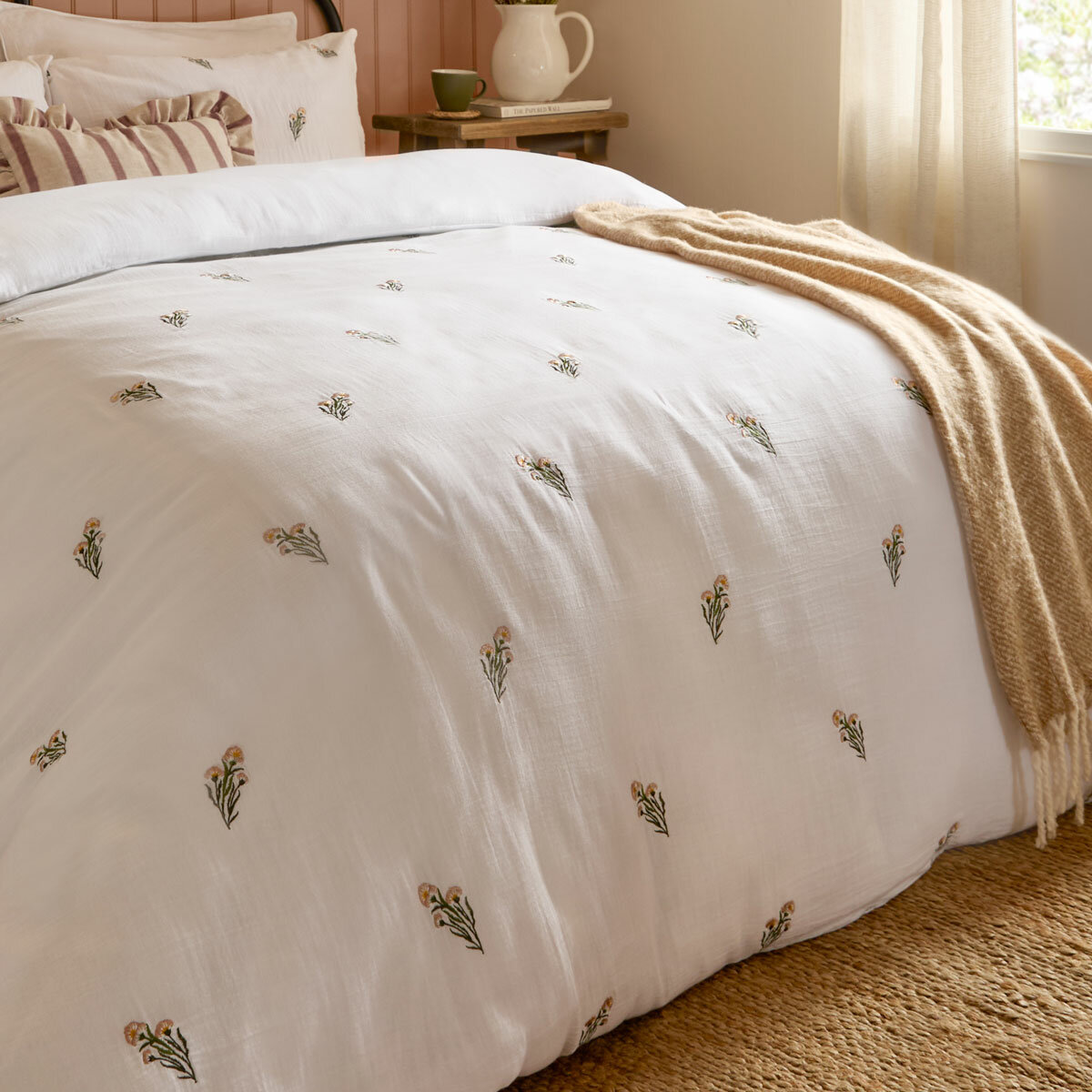 Soft white duvet set with a subtle scattered floral pattern, neatly laid across a made bed