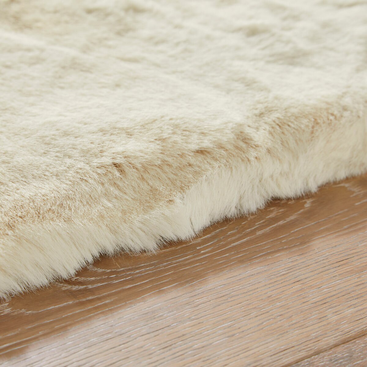 beige faux fur rug with thick, fluffy texture on wooden floor