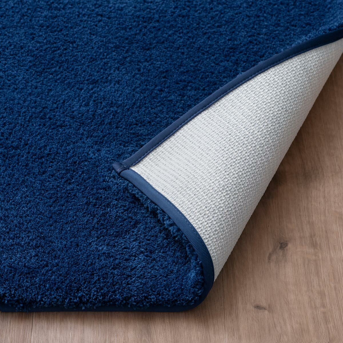 Zommed in imagery of Blue bath mat folded showcasing anti skid backing