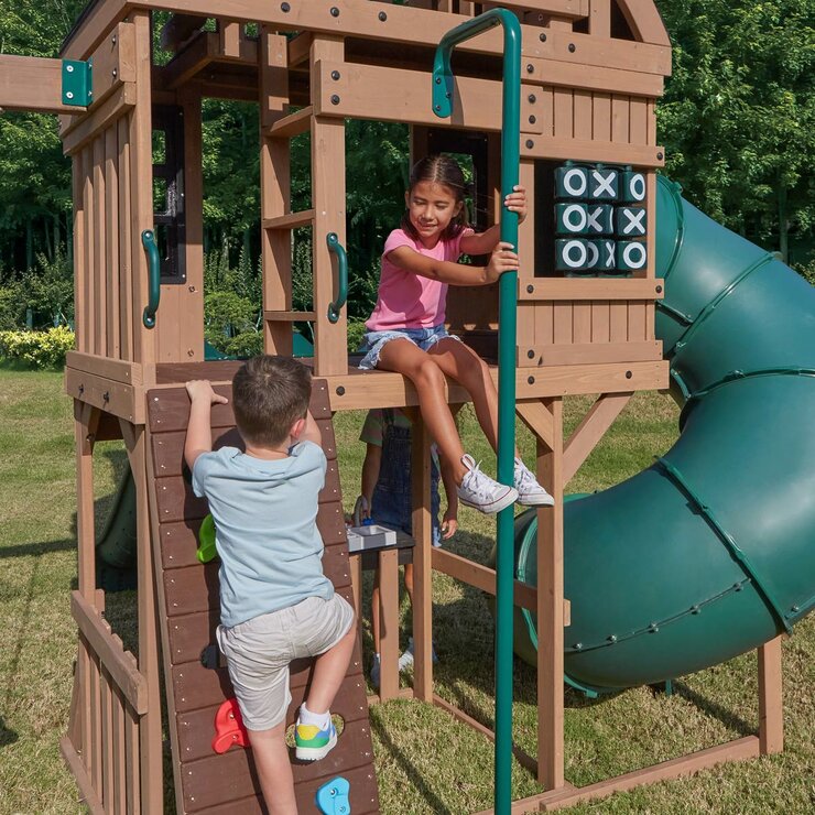 Lifestyle image of a child climbing the rock wall and another on the fireman's pole