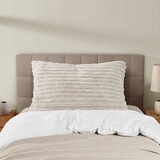 XL ribbed pillow with a plush texture propped against a tufted headboard on a neatly made bed