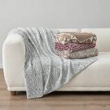 Plaid and floral throws in colours: Sage green, Taupe and black + white staged on a white sofa with minimalistic interior Plaid and floral throws in colours: Sage green, Taupe and black + white staged on a white sofa with minimalistic interior